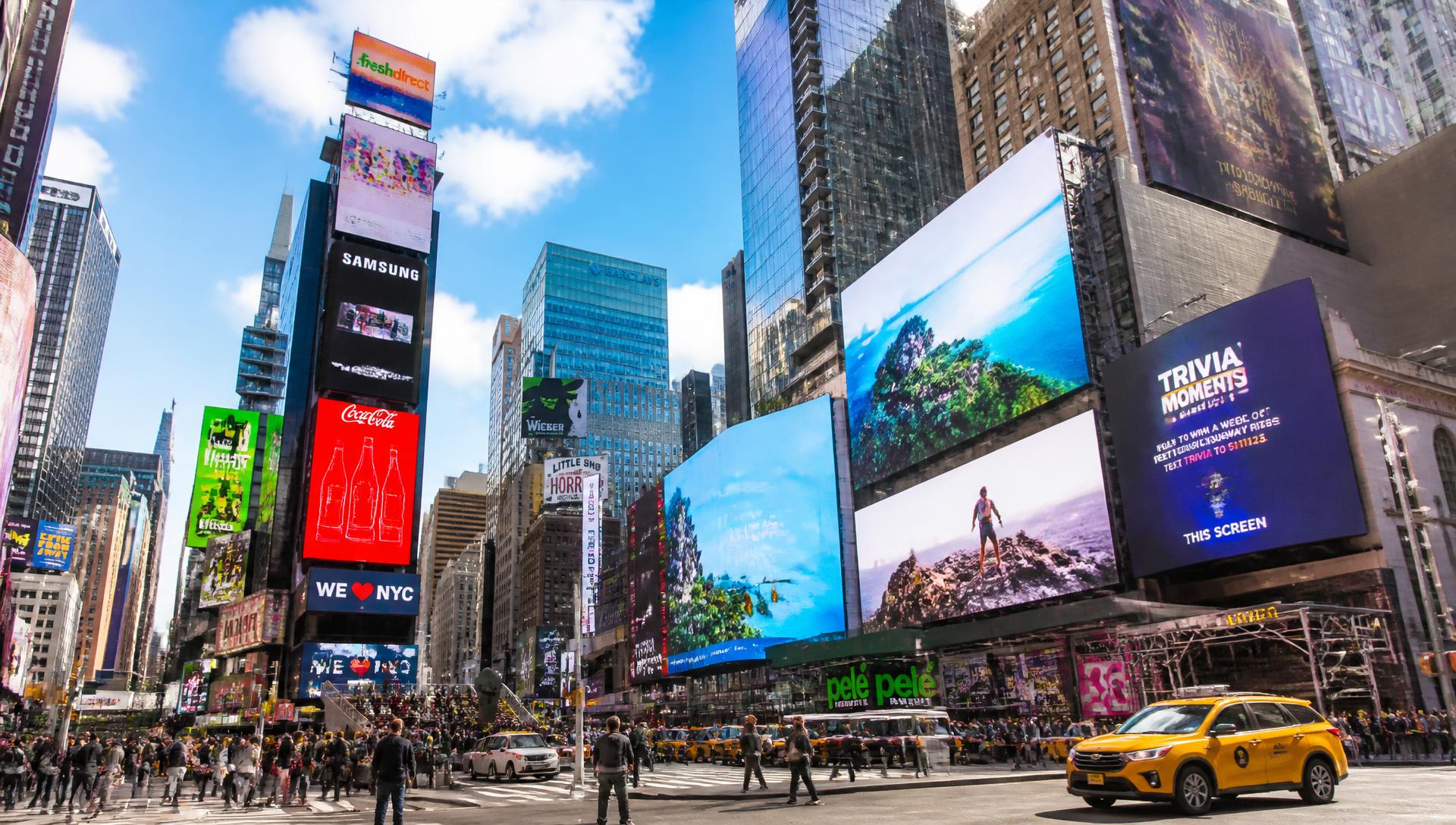 Sunny afternoon city intersection lined with large digital billboards and out-of-home advertising displays